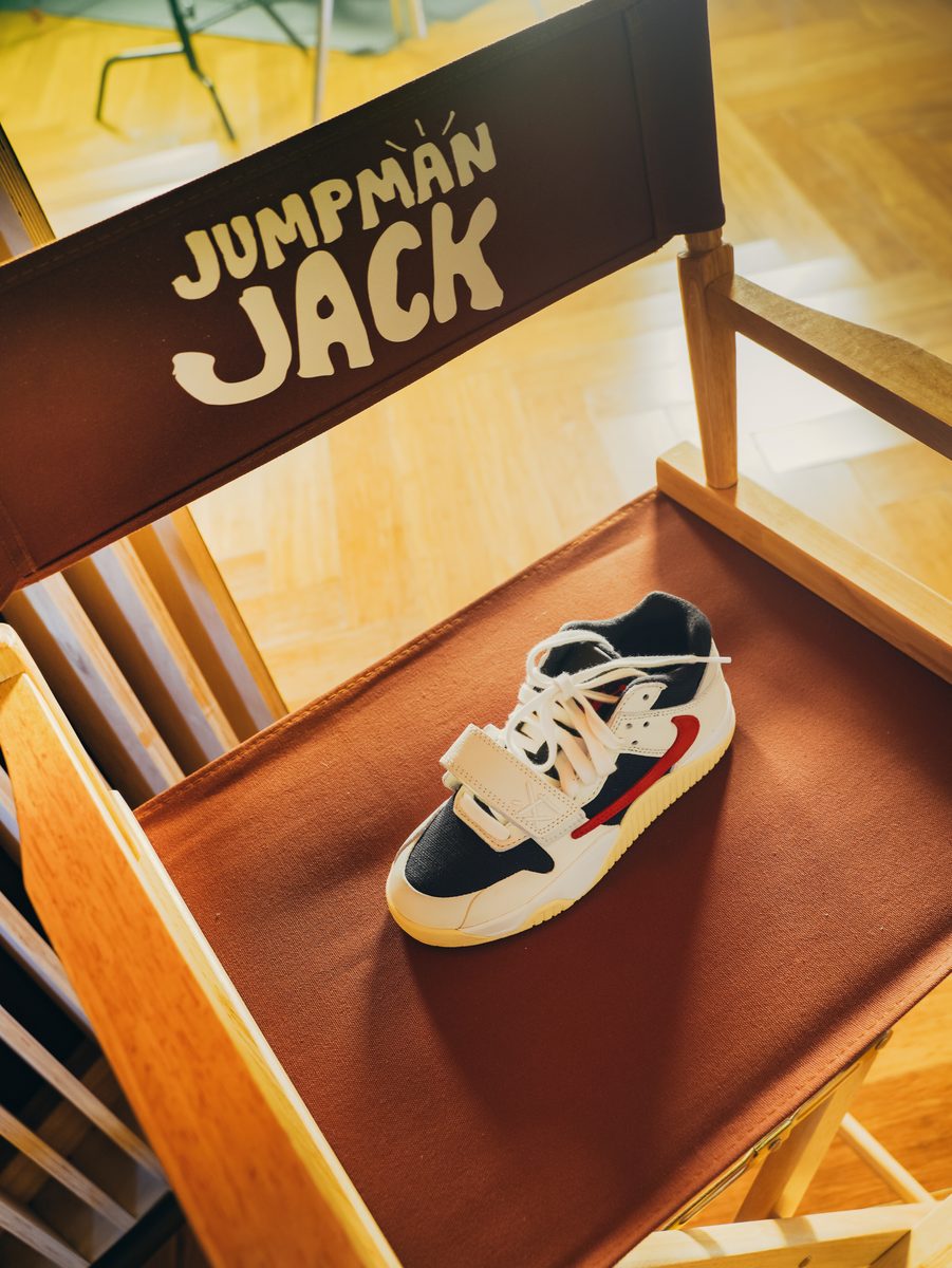 A sneaker set on a director's chair printed Jumpman Jack, in warm light.